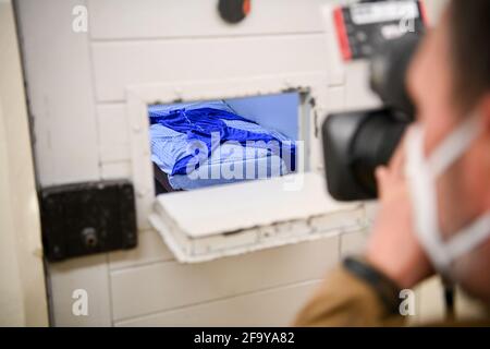 Berlino, Germania. 21 Apr 2021. Un cameraman filma attraverso il portello aperto di una porta di cella al memoriale di Berlino-Hohenschönhausen, sui terreni della ex prigione remand del Ministero della sicurezza di Stato. Il monumento è stato ricostruito e ristrutturato. Credit: Jens Kalaene/dpa-Zentralbild/dpa/Alamy Live News Foto Stock