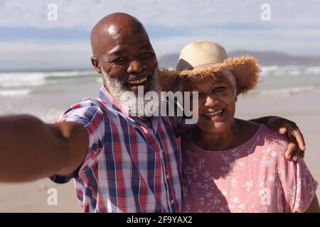 Ritratto di felice coppia afro-americana senior che prende un selfie in spiaggia Foto Stock