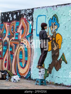 Giovane artista di strada che dipinge nuove opere d'arte di strada a Mauerpark, Prenzlauer Berg, Berlino, Germania Foto Stock