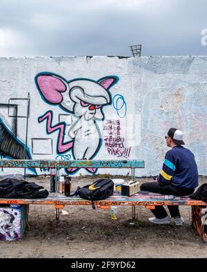 Giovane artista di strada che dipinge nuove opere d'arte di strada a Mauerpark, Prenzlauer Berg, Berlino, Germania Foto Stock