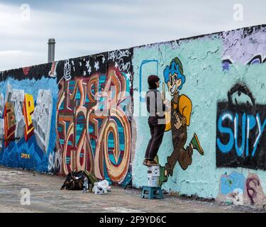 Giovane artista di strada che dipinge nuove opere d'arte di strada a Mauerpark, Prenzlauer Berg, Berlino, Germania Foto Stock