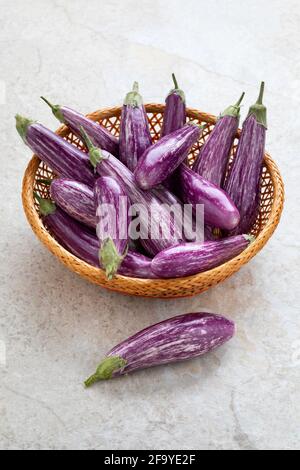 Cestino con mini melanzane biologiche a strisce viola fresche Foto Stock