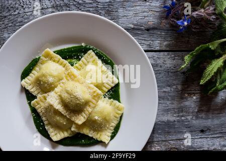 Ravioli ripieni di patate e carote su un letto di Purea di borragine con una spruzzata di parmigiano e nero pepe Foto Stock