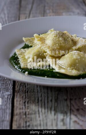 Ravioli ripieni di patate e carote su un letto di Purea di borragine con una spruzzata di parmigiano e nero pepe Foto Stock