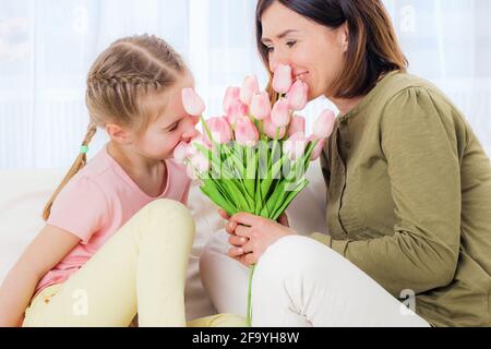 Mamma e ragazza felici che si godono la giornata delle madri sul divano, rilassante Foto Stock