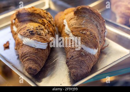 Croissant integrali ripieni di crema su un vassoio di acciaio. Colazione al bar. Umbria, Italia, Europa Foto Stock