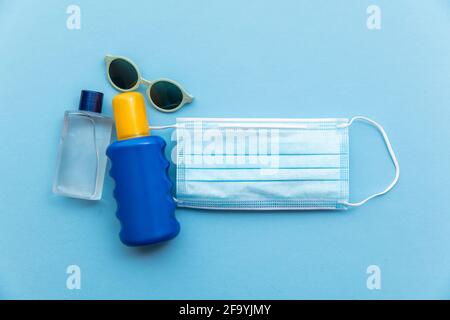 Crema solare e biberon igienizzante su una maschera medica protettiva. Covid estate Foto Stock