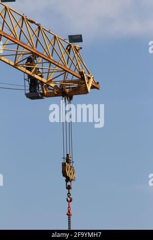 Italia, 04/21/2021: Gru a torre, vista di un lavoratore, la costruzione di un nuovo edificio residenziale in un cantiere contro il cielo blu. Foto Stock