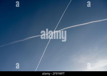 I sentieri bianchi, dallo scarico del getto, formano una croce nel cielo. Un cielo blu sullo sfondo Foto Stock