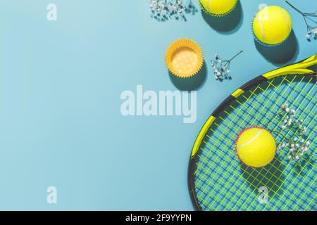 Festa di tennis. Composizione sportiva Holliday con palla da tennis gialla e racchetta su sfondo blu di campo da tennis duro Foto Stock