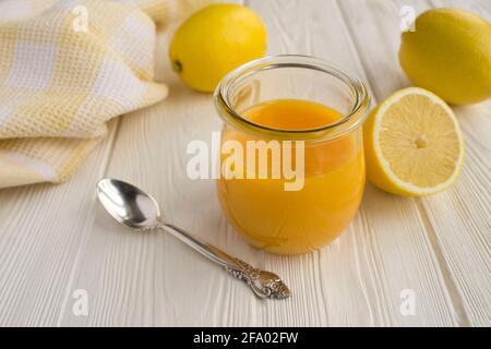 Limone curd nel vaso di vetro su sfondo bianco di legno. Primo piano. Foto Stock