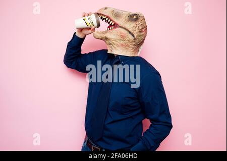 Uomo con testa di dinosauro che tiene una tazza di caffè Foto Stock