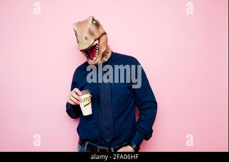 Uomo con testa di dinosauro che tiene una tazza di caffè Foto Stock