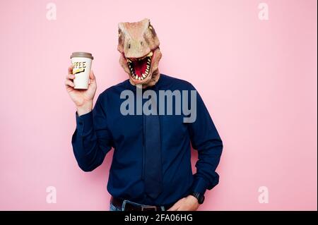 Uomo con testa di dinosauro che tiene una tazza di caffè Foto Stock