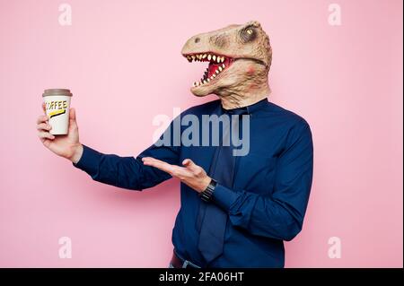 Uomo euforico con testa di dinosauro con caffè per andare Foto Stock