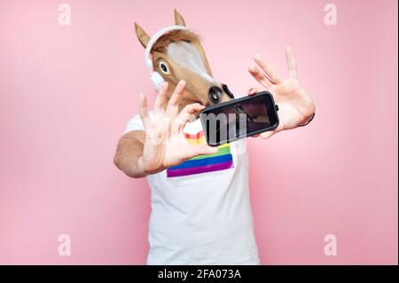 Uomo che indossa una maschera a cavallo mentre prende un selfie con lo smartphone Foto Stock