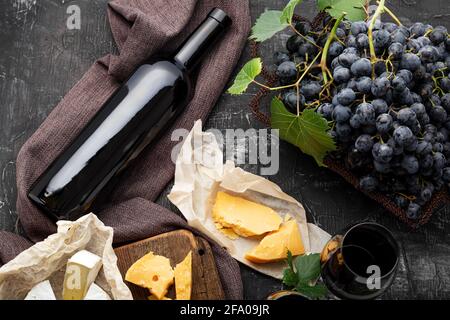 Bottiglia di vino rosso, diversi formaggi, uve. Composizione del vino d'annata ancora da vita con formaggio Camembert affinato, uva. Beffe di vino. Cena al ristorante Foto Stock