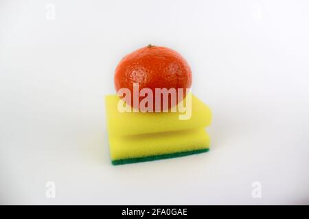 Un tangerino su una spugna verde gialla isolata su bianco sfondo Foto Stock