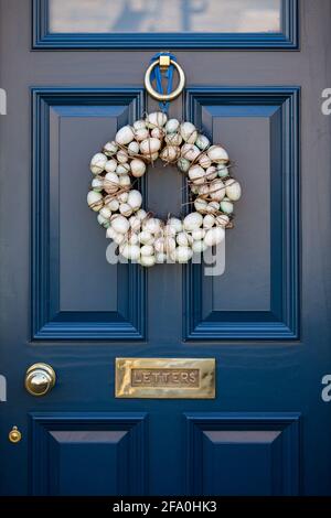 Decorazione della porta della corona dell'uovo di Pasqua su un dipinto di blu scuro Porta d'ingresso in un villaggio inglese in primavera Foto Stock