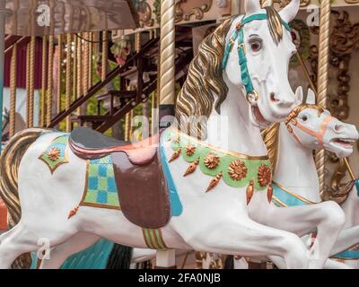Closeup di una figura di cavallo con bastoni e selle come posti a sedere in una tradizionale carosello colorato vecchio stile all'aperto. Divertimento per tutta la famiglia d'epoca. Foto Stock