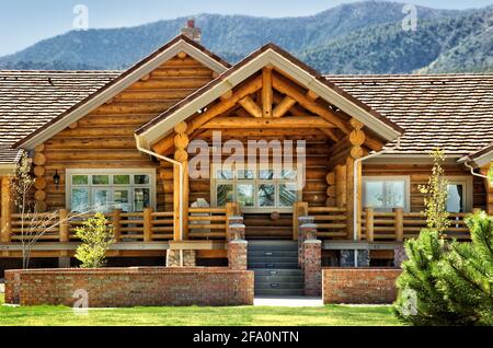 Una vista esterna di una moderna cabina in legno, con un'area patio e una facciata in terra contemporanea. Foto Stock