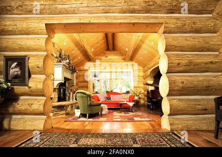 Un lussuoso soggiorno, con camino, piano e arredi confortevoli, in una moderna cabina in legno in montagna. Foto Stock