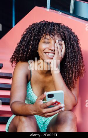 Sorridente donna africana utilizzando il suo smartphone Foto Stock