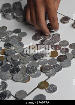 Uomo che conta il centesimo indonesiano. Moneta di Rupiah impilata. Foto Stock