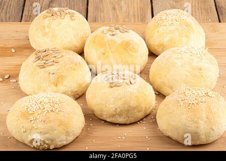 Panini appena sfornati con sesamo e semi di girasole su un tagliere. Stile rustico. Foto Stock