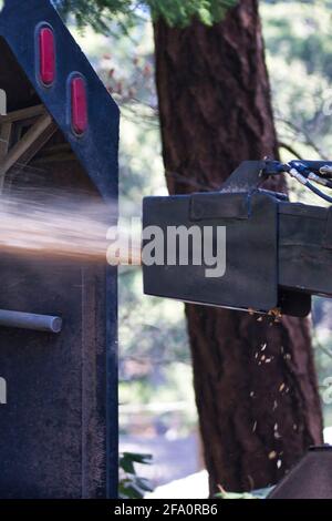 alimentazione di arti grandi o di un albero abbattuto attraverso un woodchipper Foto Stock