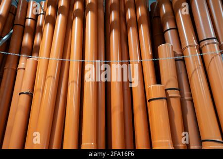 Pila di tubi di canalizzazione U in PVC su un magazzino di ferramenta. Disposti su un mucchio di tubi di plastica marrone. Industriale per tubi idraulici per cantieri esterni. Con Foto Stock