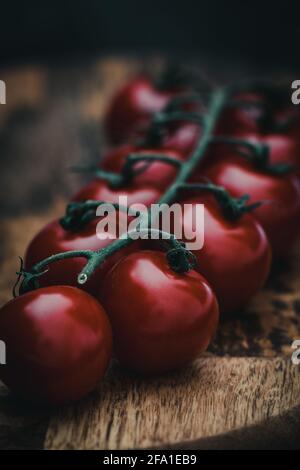 Primo piano verticale di pomodori ciliegini rossi su tavola di legno Foto Stock