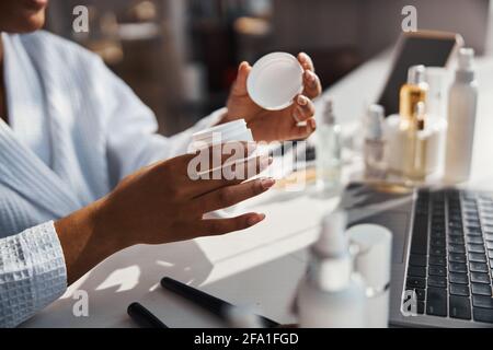 Le mani femminili tengono il vaso di crema cosmetica Foto Stock