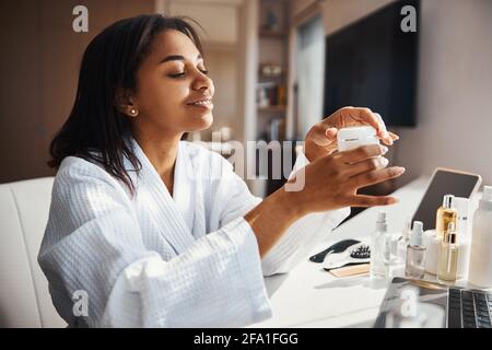 Giovane donna allegra che tiene il vaso di crema cosmetica Foto Stock