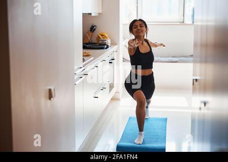 Attraente giovane donna che pratica yoga a casa Foto Stock