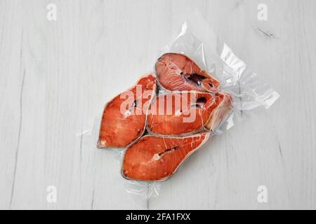 Vista dall'alto della bistecca di salmone crudo nell'imballaggio sottovuoto sfondo chiaro Foto Stock