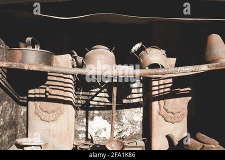 Pentole e padelle su rack in vecchia stufa arrugginita Foto Stock