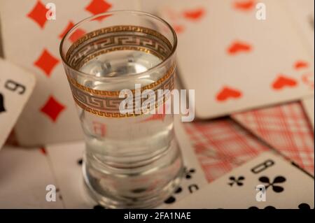 Carte da gioco e un bicchiere di vodka su un tavolo coperto di burlap grossolano. Primo piano, messa a fuoco selettiva. Foto Stock