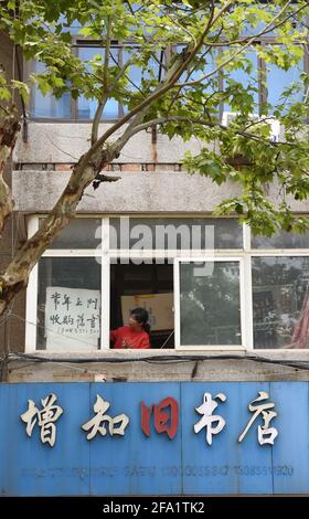 (210422) -- HEFEI, 22 aprile 2021 (Xinhua) -- Chen Guixia esamina un annuncio di raccolta di libri alla libreria di Zengzhi a Hefei, provincia di Anhui della Cina orientale, 19 aprile 2021. Sin dalla sua apertura 21 anni fa, Zengzhi Bookshop, un non descritto rivenditore di libri di seconda mano nel centro di Hefei, è stato salutato come un punto di riferimento intellettuale tra i fan del libro locale. Il suo ultimo proprietario, Zhu Chuanguo, vantava una collezione di 20,000-strong libri usati, tutti che erano stati acquistati dai lettori ordinari e riciclando i Outlets.Under Zhu's visione, uno dei libri gettati-off può risultare essere illuminante a qualcun altro che quindi dese Foto Stock