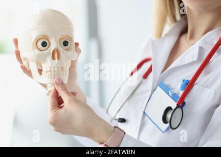 Medico con stetoscopio che mostra le mascelle sul closeup del cranio umano Foto Stock