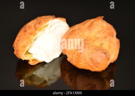 Una mezza e una chouquette intera dolce, primo piano, isolata su nero. Foto Stock