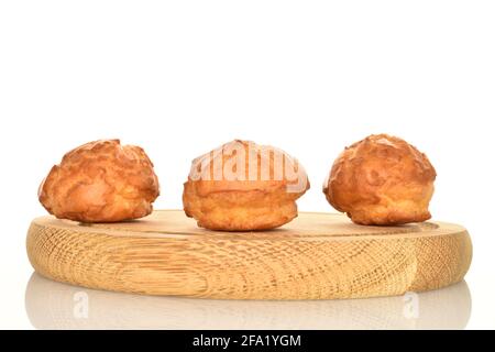 Tre chouquettes fresche su un vassoio rotondo di bambù, su uno sfondo bianco. Foto Stock