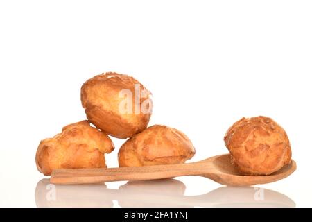 Quattro chouquettes dolci con un cucchiaio di legno, primo piano isolato su bianco. Foto Stock