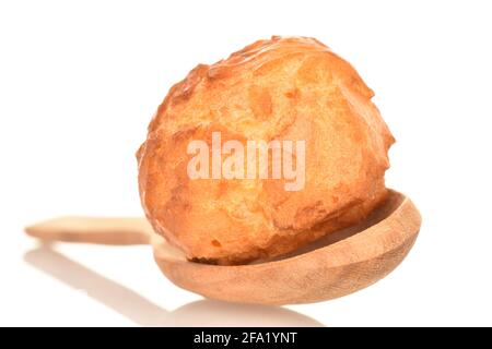 Una chouquette dolce con un cucchiaio di legno, primo piano isolato su bianco. Foto Stock