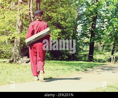 Vista posteriore di una donna che tiene un tappetino in un parco, concetto di benessere all'aperto Foto Stock