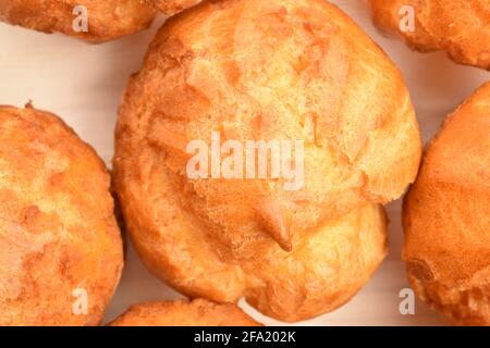 Diverse chouquettes fresche profumate su un tavolo di legno, primo piano, vista dall'alto. Foto Stock