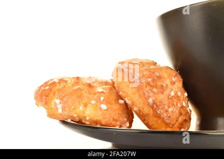 Due chouquette dolci con una tazza su un piatto, primo piano, isolato su bianco. Foto Stock