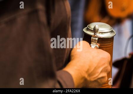 Un uomo tiene a mano la tazza di birra con coperchio Foto Stock
