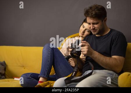 Ragazza e ragazzo che riesaminano il video sullo schermo della fotocamera digitale DSLR Foto Stock