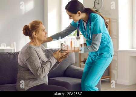 Infermiera che dà un bicchiere d'acqua alla donna anziana a casa, in clinica o in una struttura di vita assistita Foto Stock